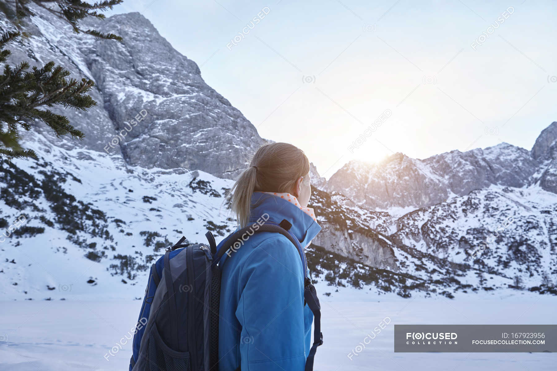 Giovane donna che cammina sulla neve e guarda il sole sulla cima della  montagna, Austria — Natura, Temperatura fredda - Stock Photo