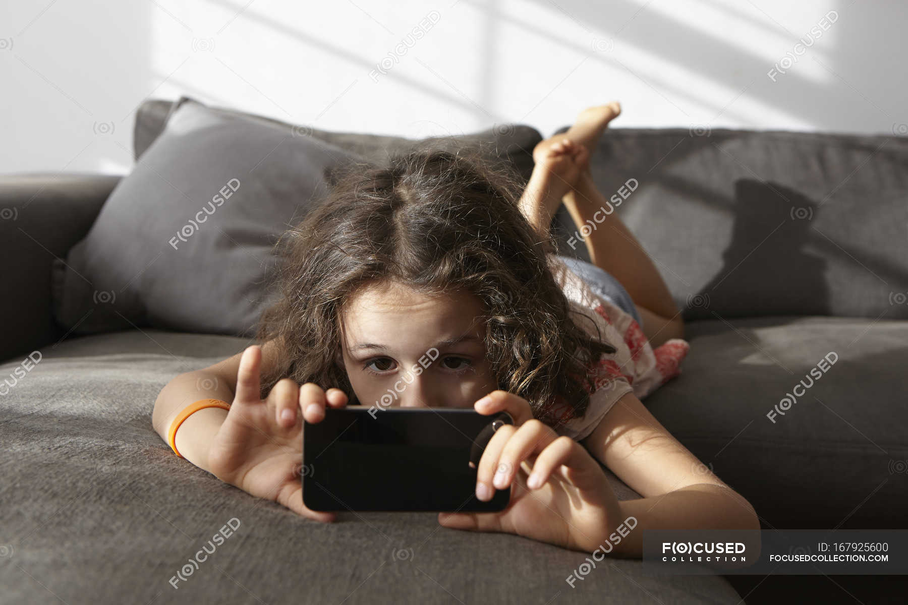 Девушка лежит на диване в гостиной и смотрит на смартфон — Дома, Гостиная -Stock Photo