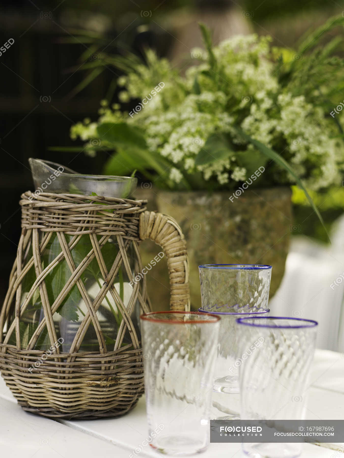 Vintage wicker jug and drinking glasses on garden table — outdoors
