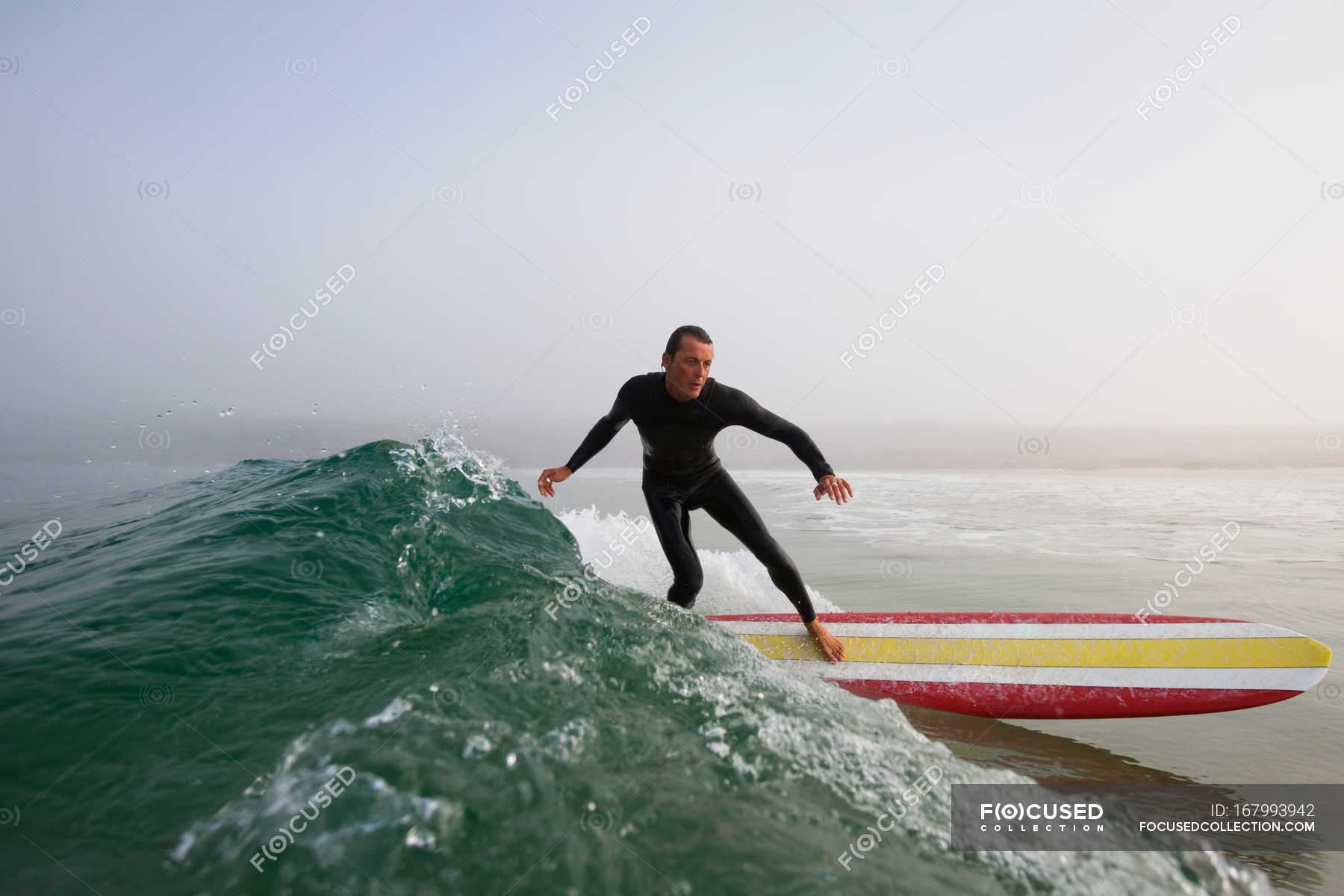 Man in swimming costume surfing a ocean wave, boobys bay, cornwall ...