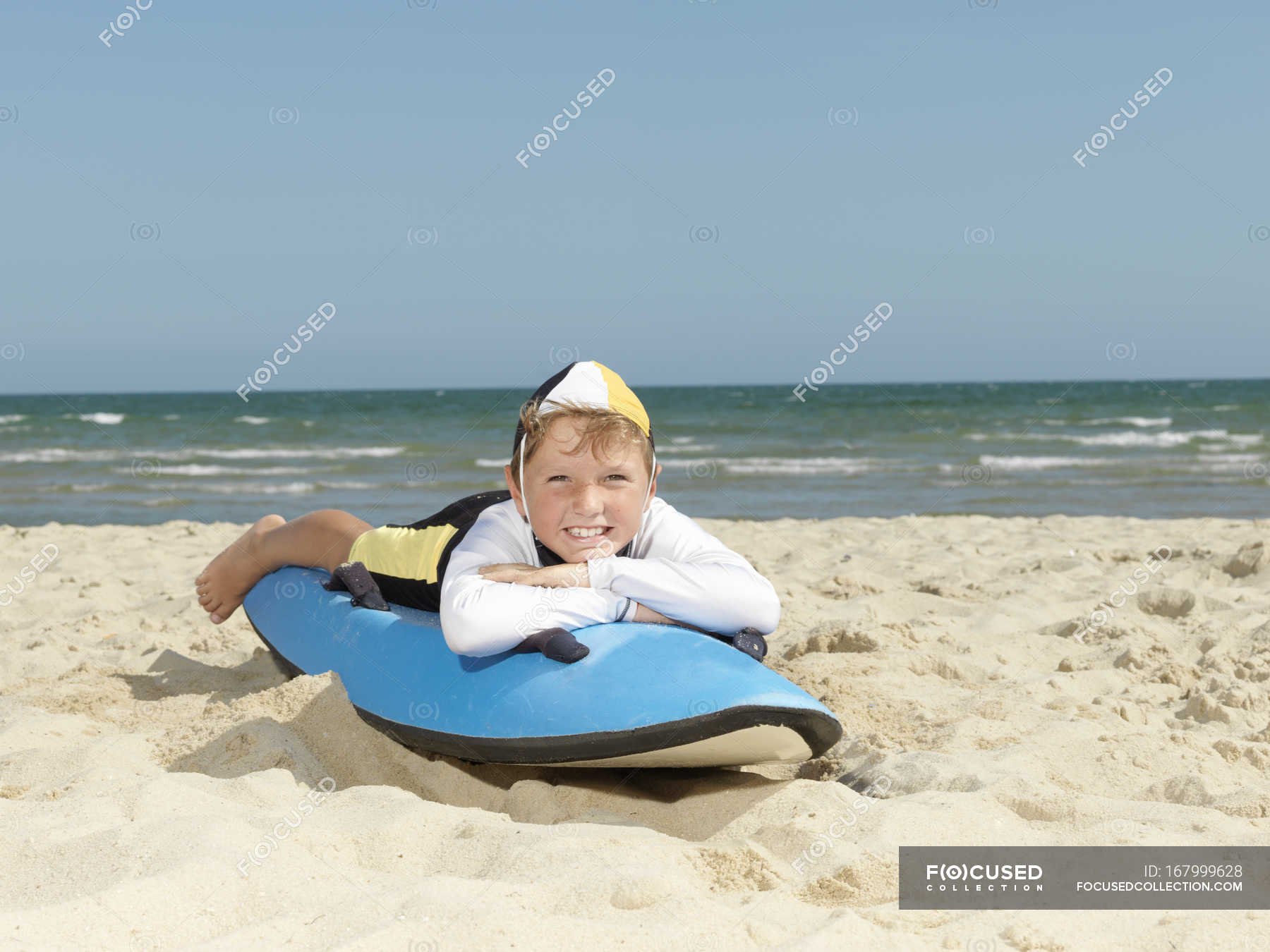 Portrait of boy nipper (child surf life savers) lying on surfboard at ...