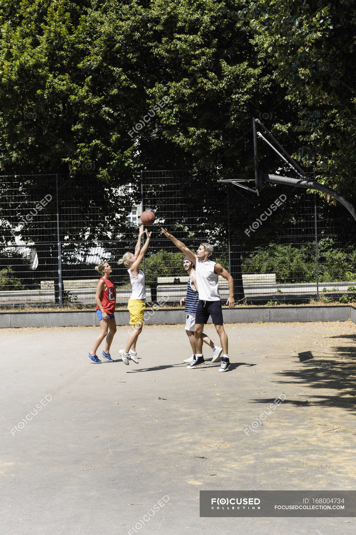 Grupo de amigos jogando basquete em uma quadra pública ao ar livre