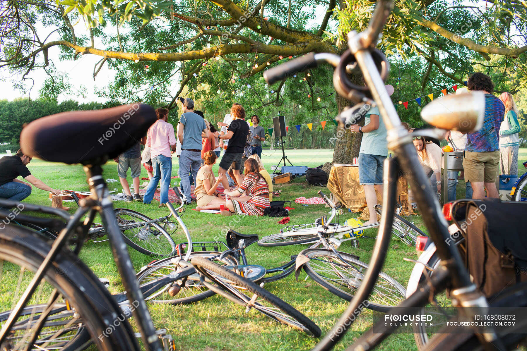 Happy Adult Crowd At Sunset Party In Park — Young Woman Cycling