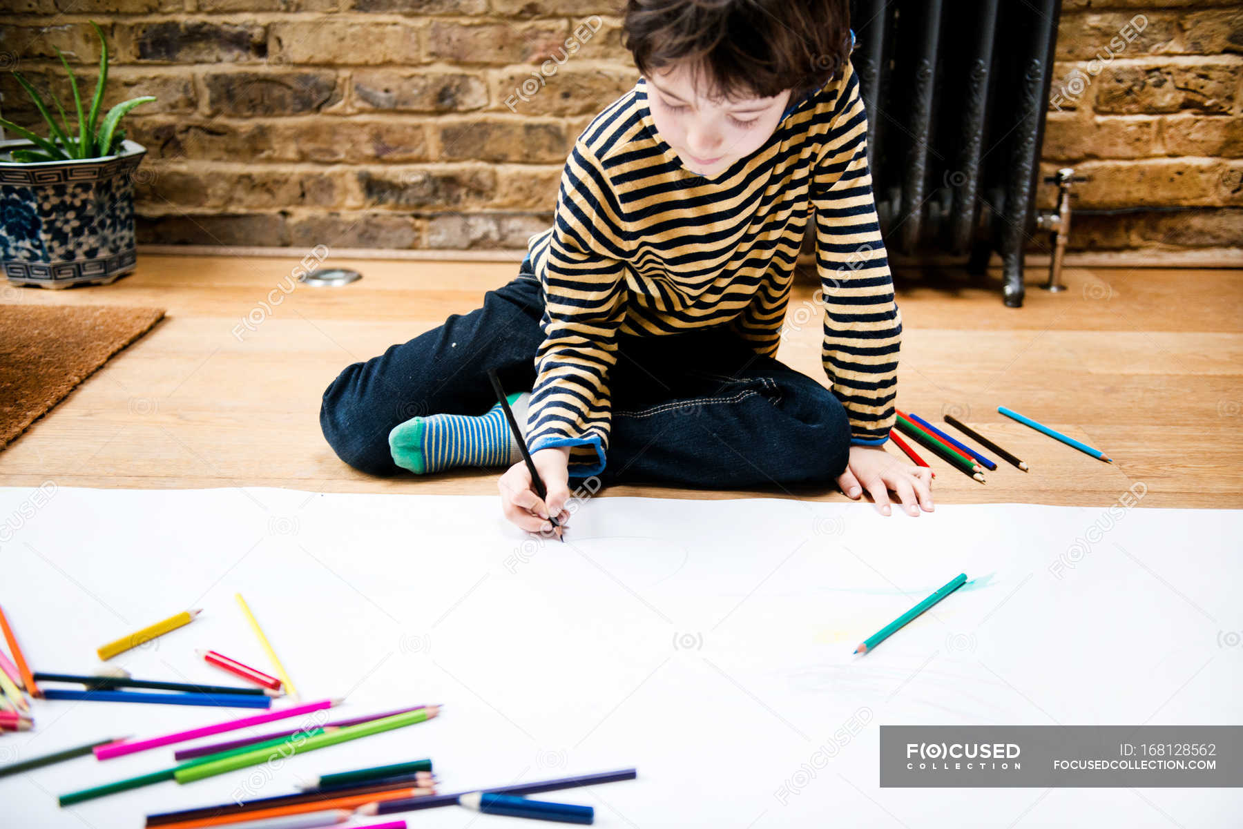 Boy sitting on floor drawing on large paper — person, Enjoyment Stock