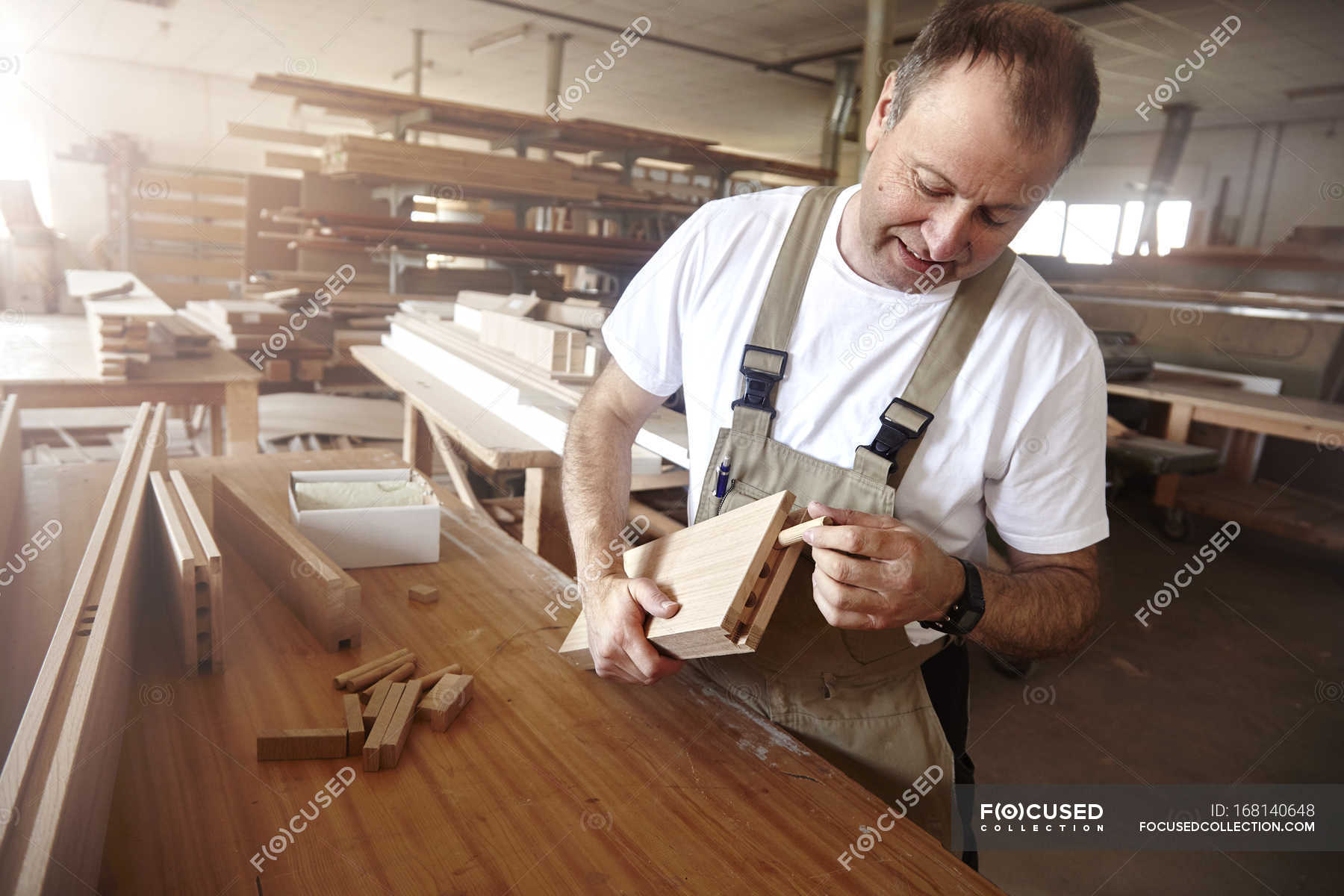 Vista laterale dell'uomo falegname in grembiule che lavora con assi di  legno — da 50 a 54 anni, fatto a mano - Stock Photo