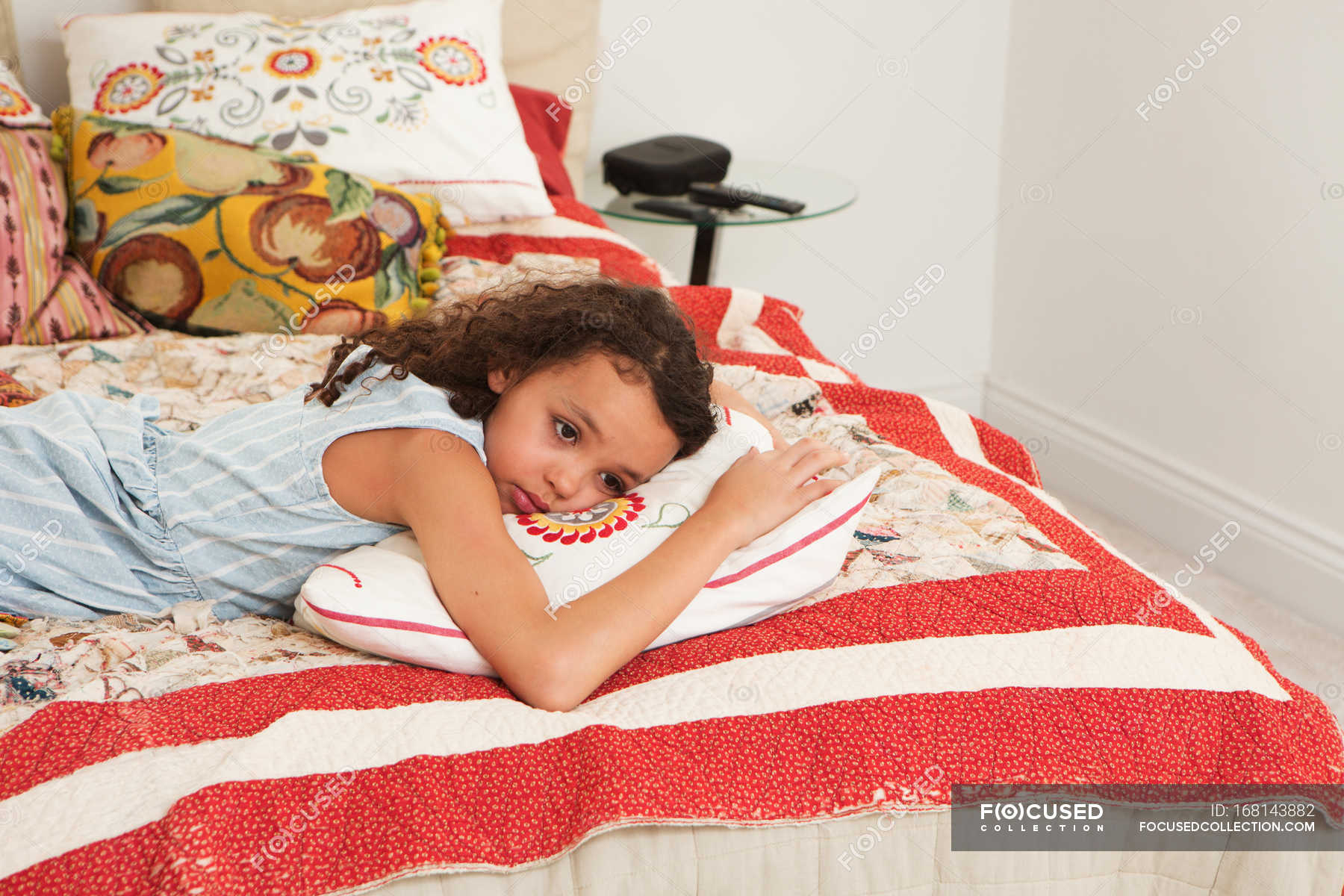 Грустная девушка лежит на кровати с подушками — лицо, Дома - Stock .