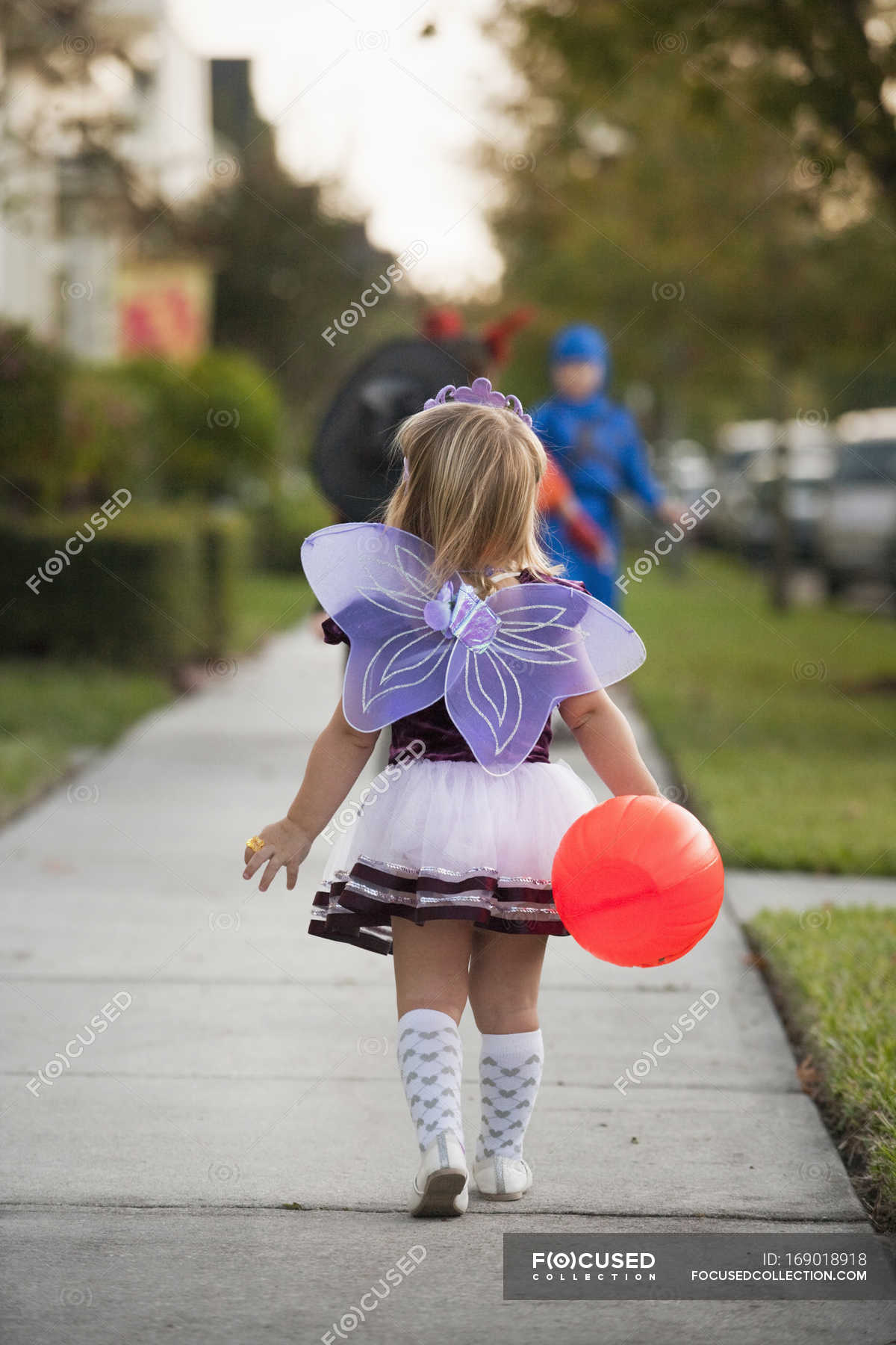 Rear view of little girl in costume going trick or treating