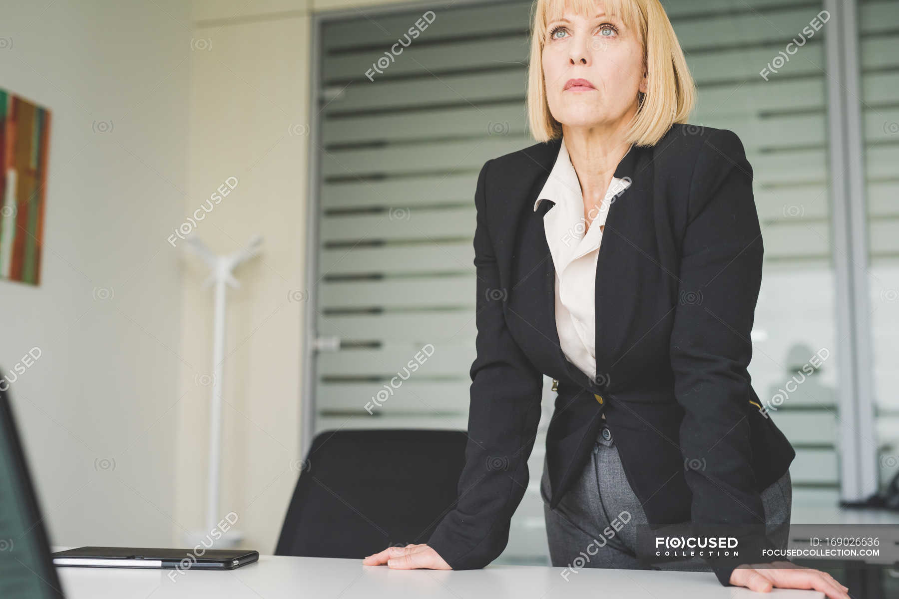 Serious mature businesswoman leaning forward on office desk — preparation, blond hair Stock
