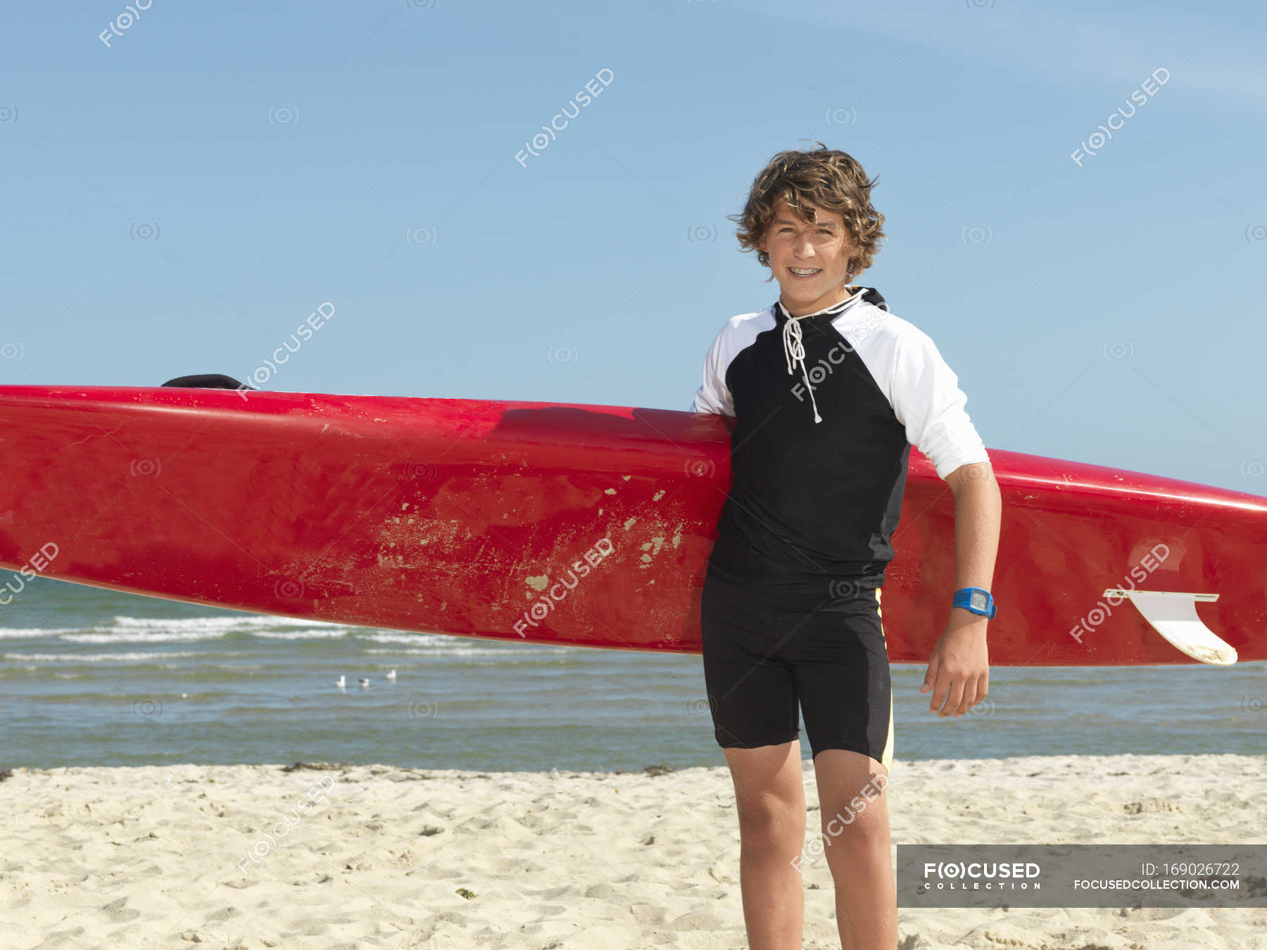 Portrait of teenage boy nipper (child surf life savers) with surfboard ...
