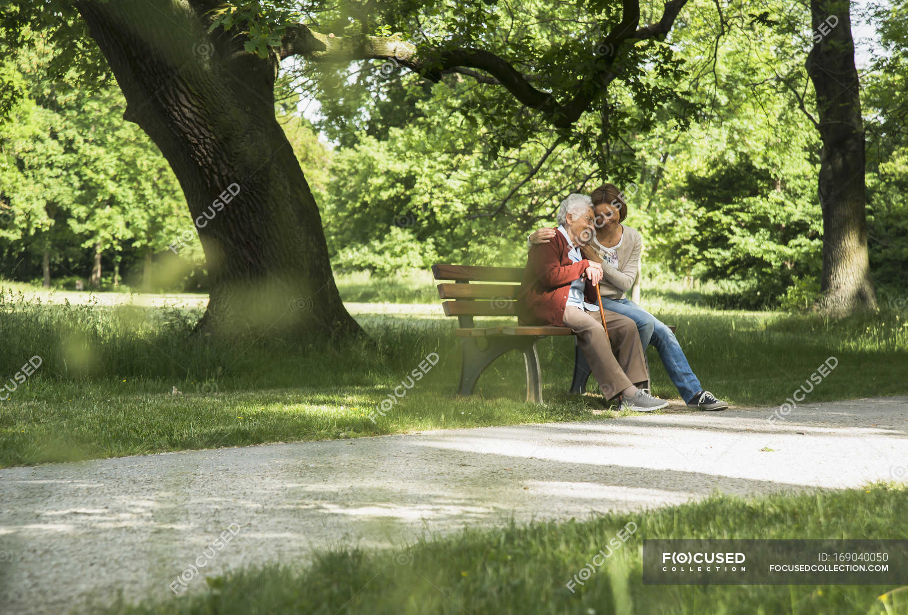 Senior woman sitting on park bench with granddaughter — tender, health ...