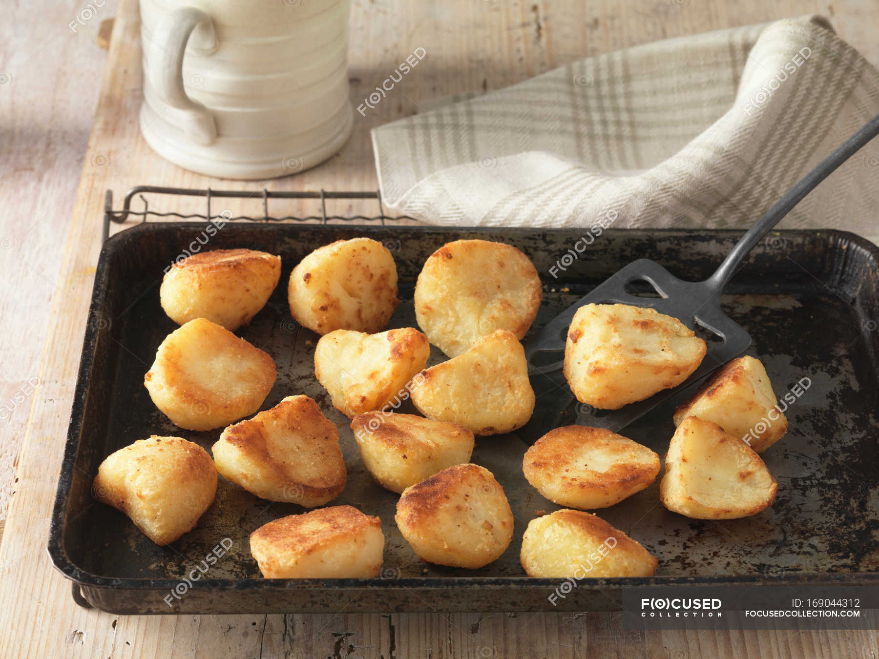 Beef dripping roast potatoes on baking tray and wire rack — nobody, indoors Stock Photo