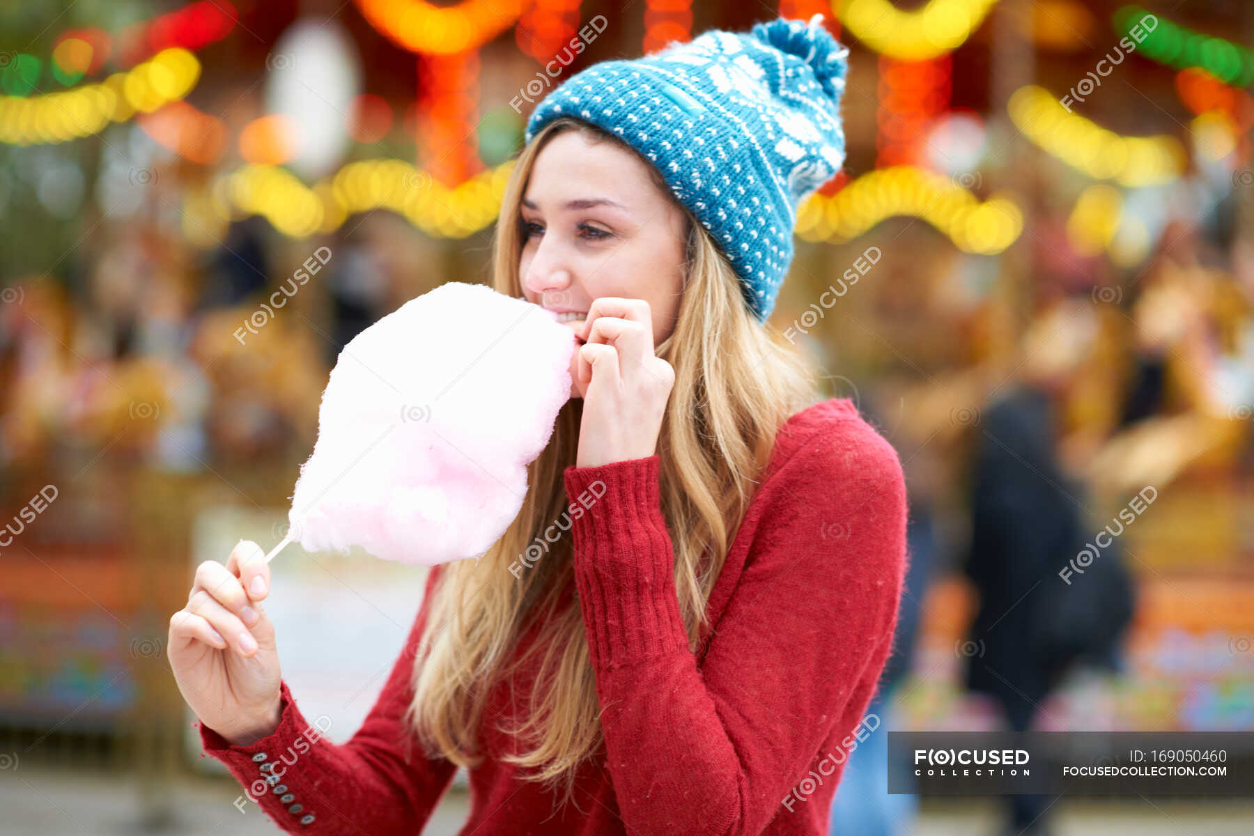 Young woman eating candy floss at funfair, outdoors — happiness, female Stock Photo 169050460