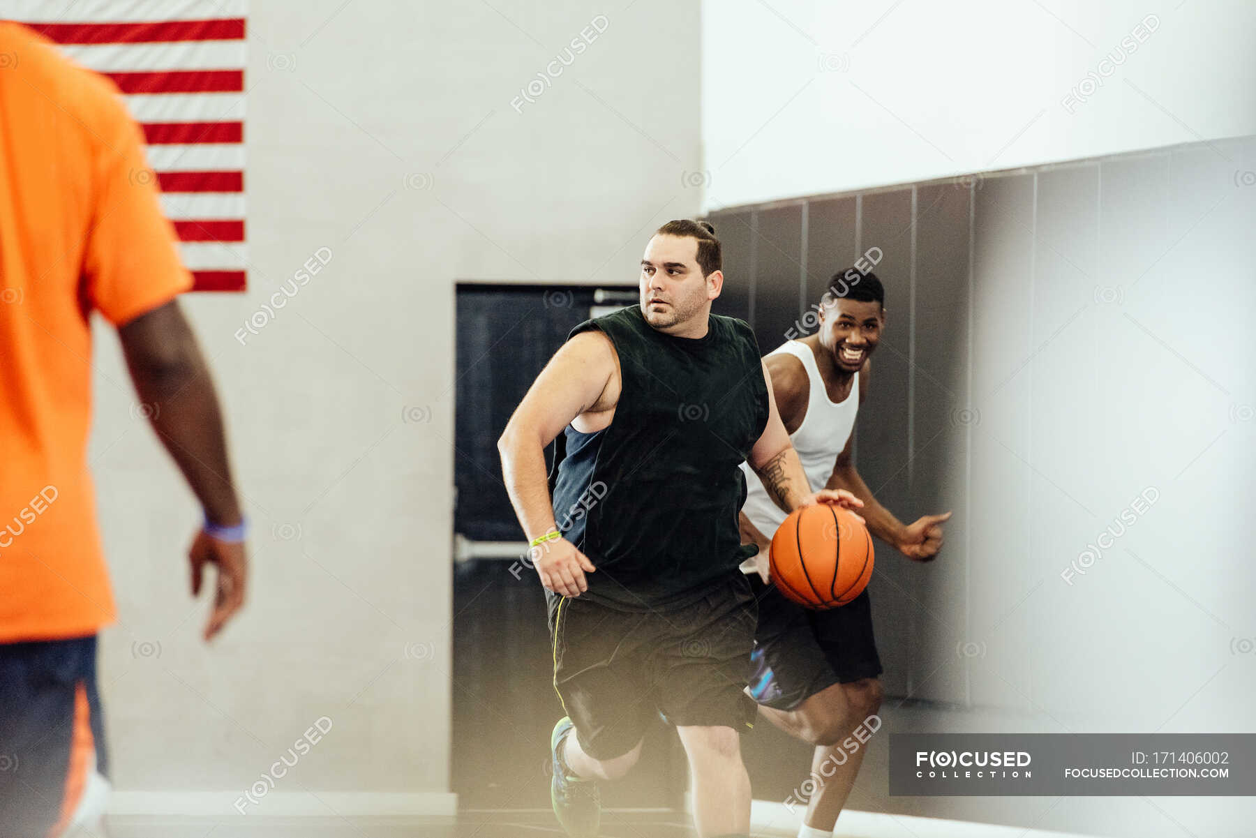 Male basketball player running with ball in basketball game — teamwork, 20 to 24 years Stock