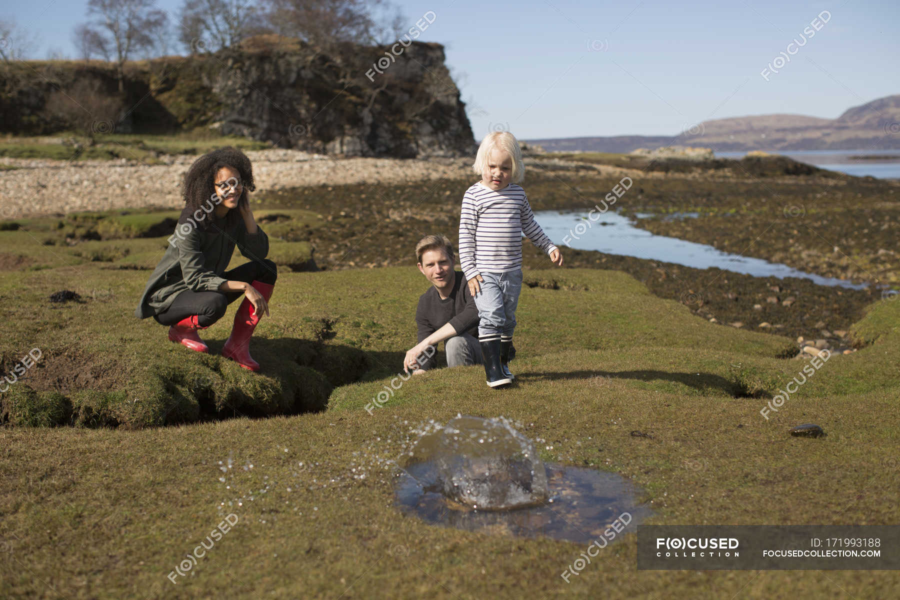 Boy throwing rock into puddle, Isle of Skye, Hebrides, Scotland — water