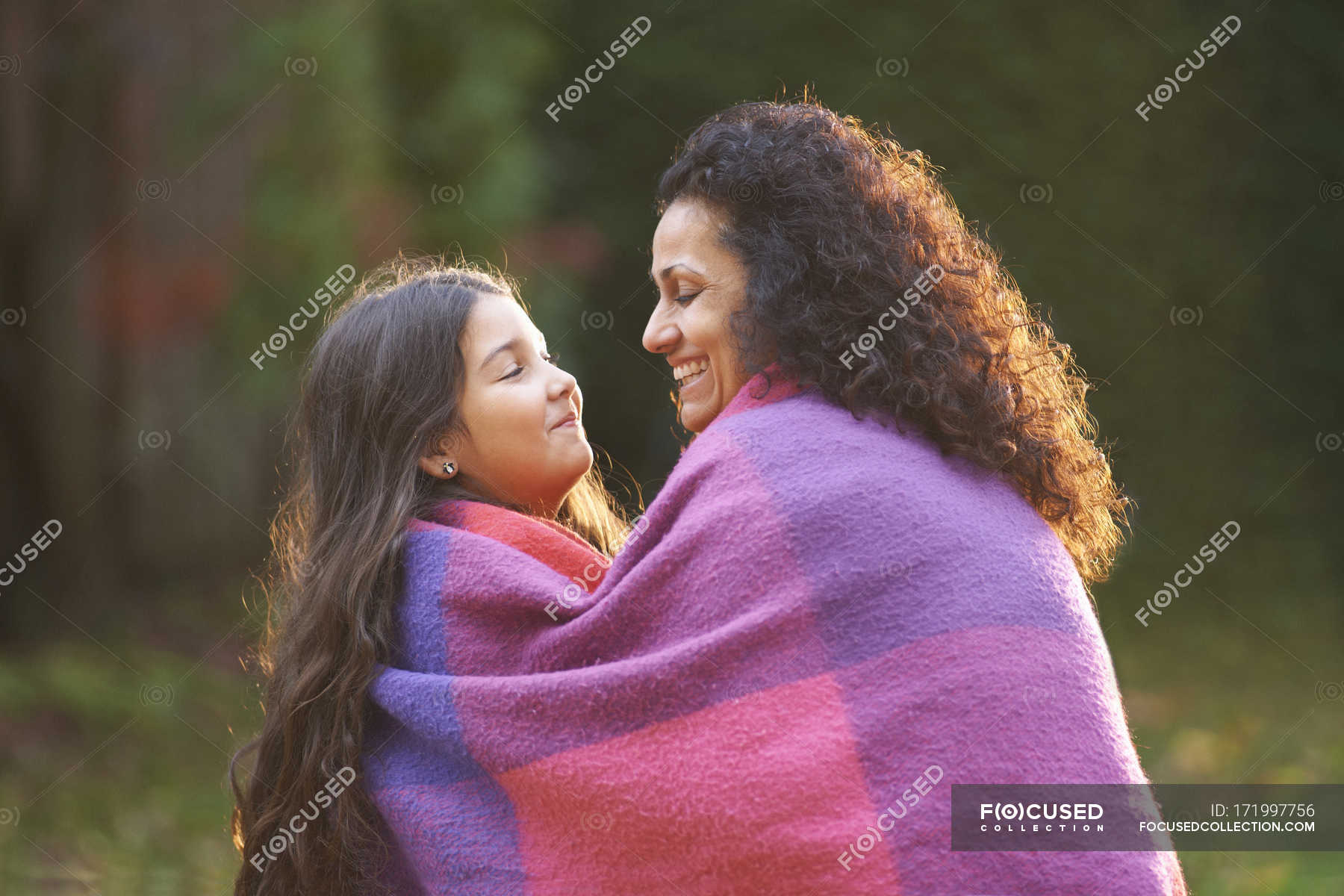 Mother and daughter wrapped in blanket in garden — pink, parent Stock