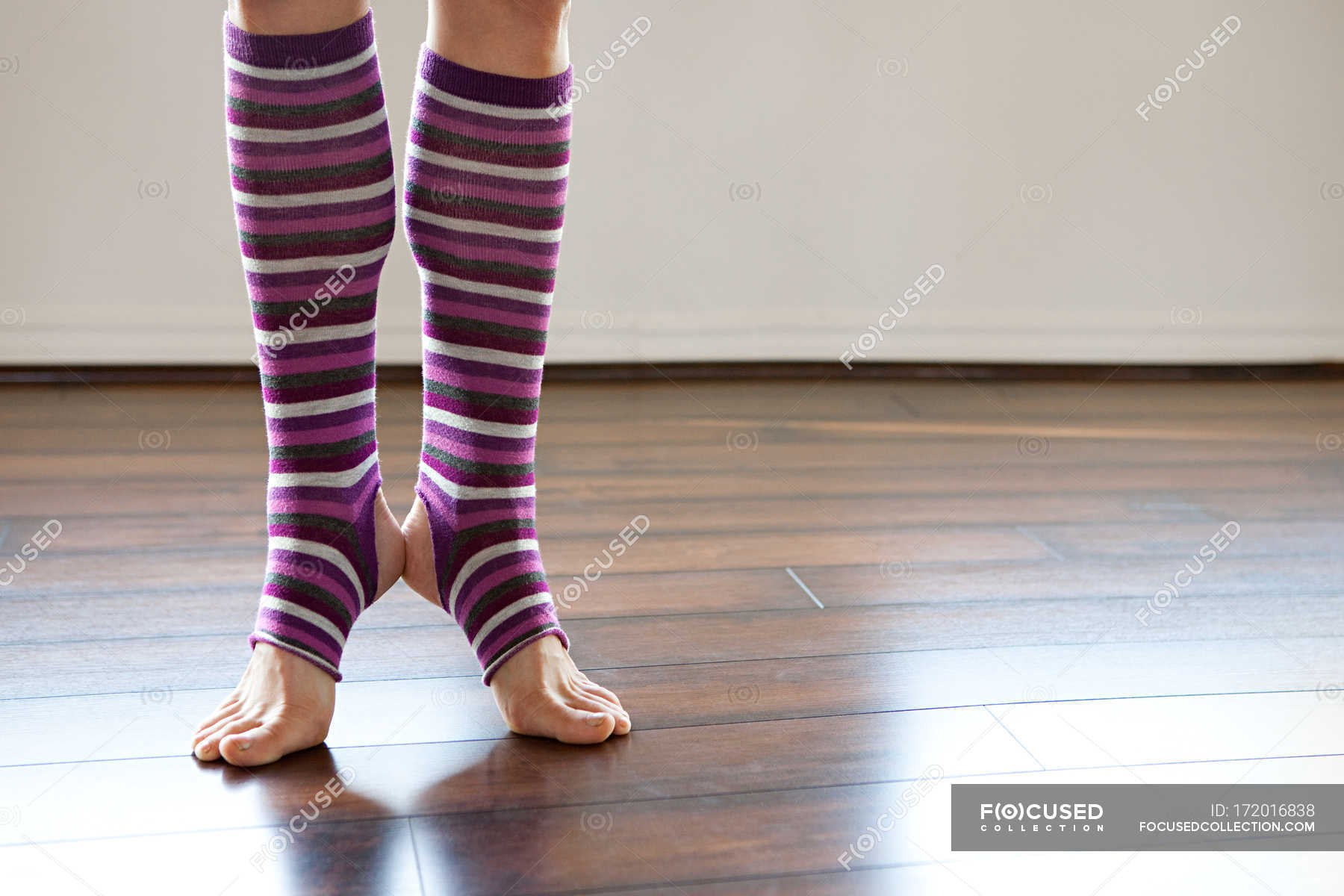 Woman wearing stripey legwarmers on tiptoe — close up, Wooden Floor ...
