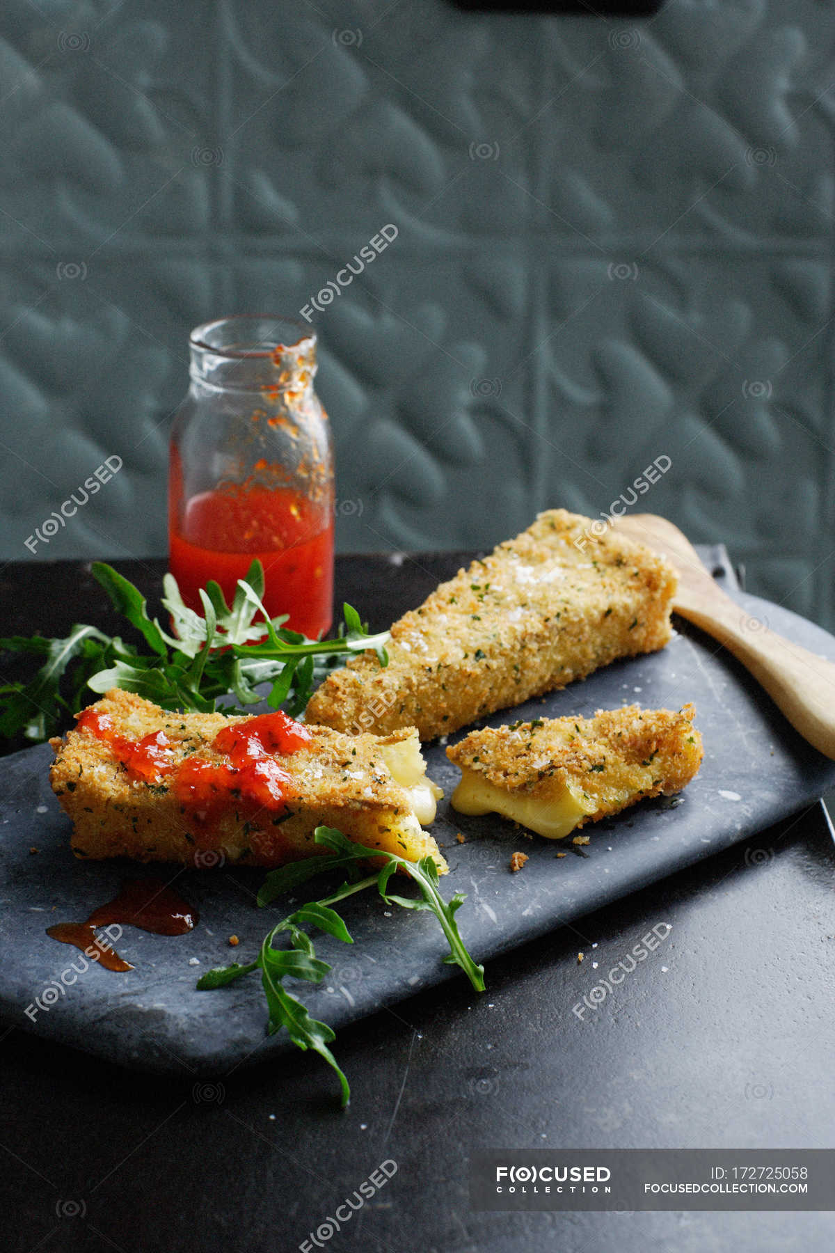 Deep fried slices of brie cheese with hot sauce — fresh, garnish