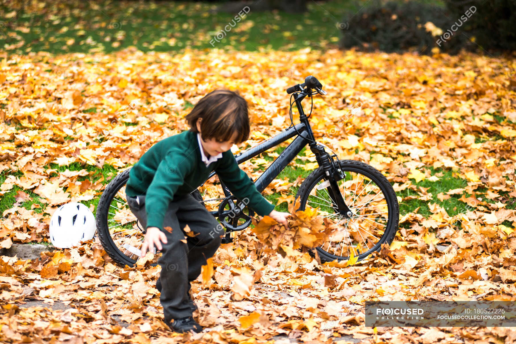 Boy in park with bike playing in autumn leaves — Full Length, one ...