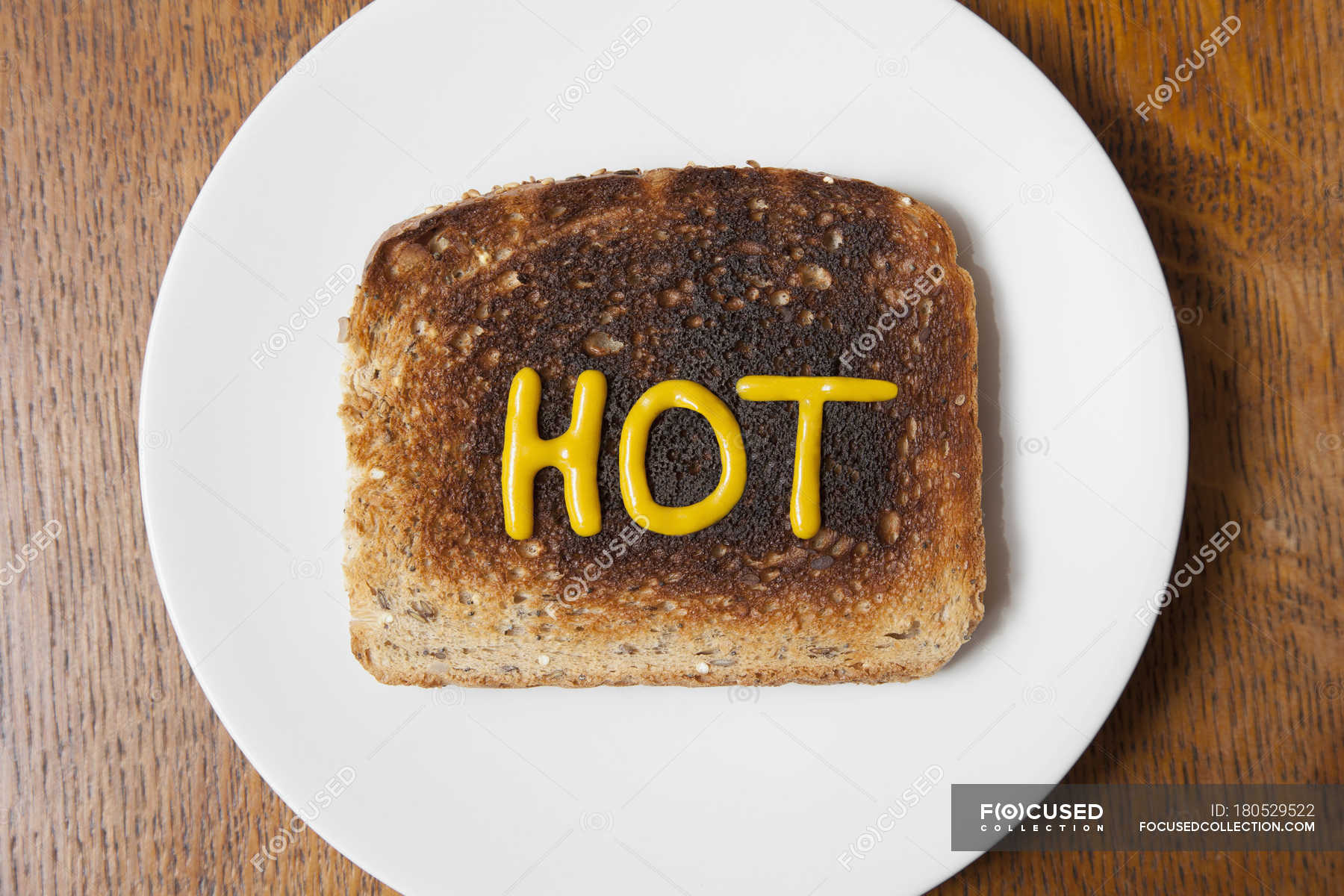 Top view of the word hot written in mustard on burnt toast — daylight