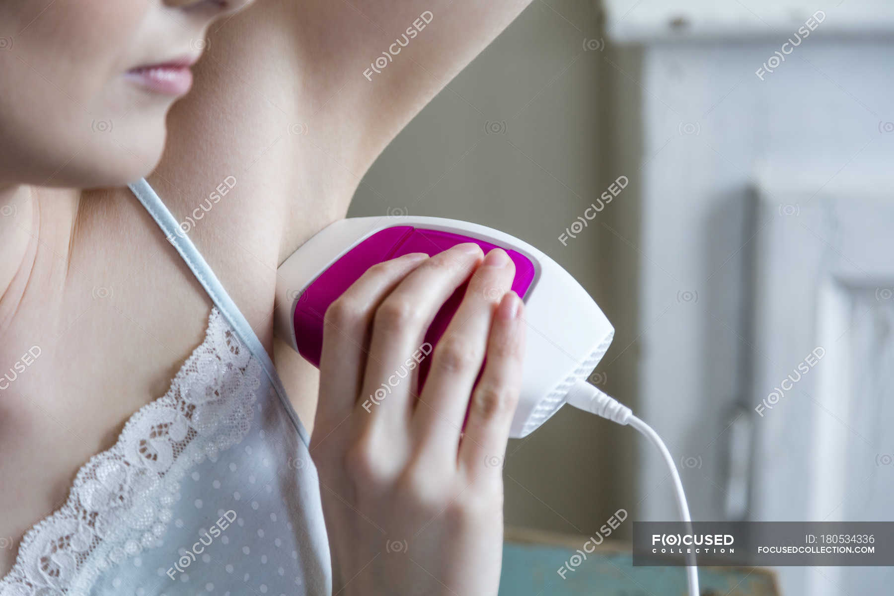 Cropped View Of Woman Using Electric Shaver To Shave Armpit Indoors