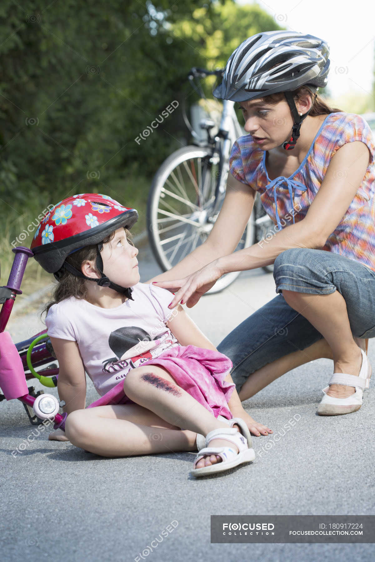 Mother caring for daughter fallen off bicycle — mid adult woman, woman