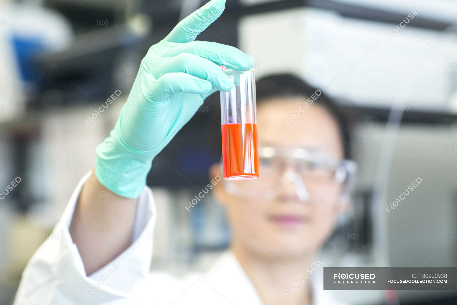 young-female-lab-technician-holding-up-orange-sample-in-lab-scientist