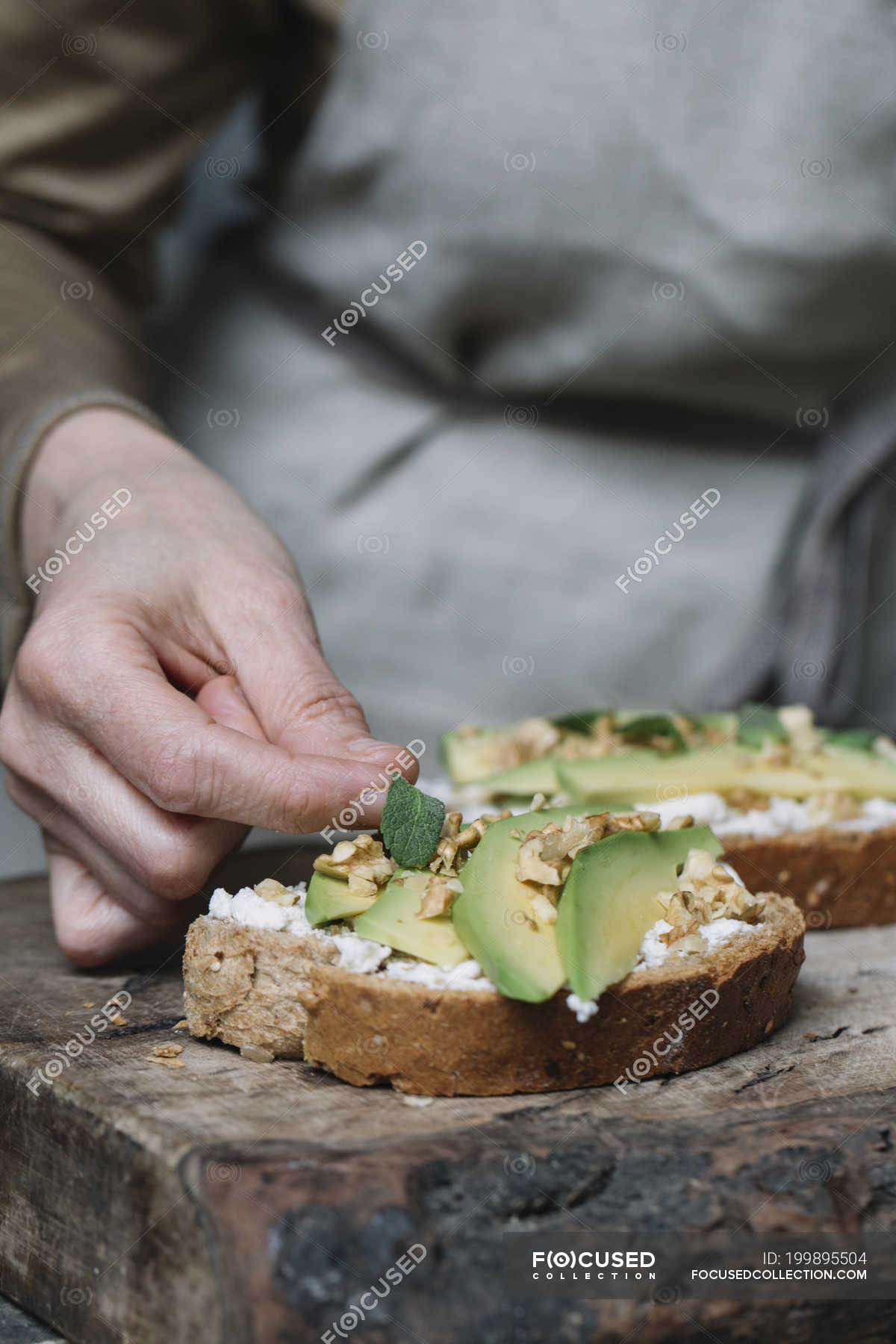 Woman Placing Herbs On Ricotta Avocado And Walnut Bruschetta Close Up Fresh Mid Section