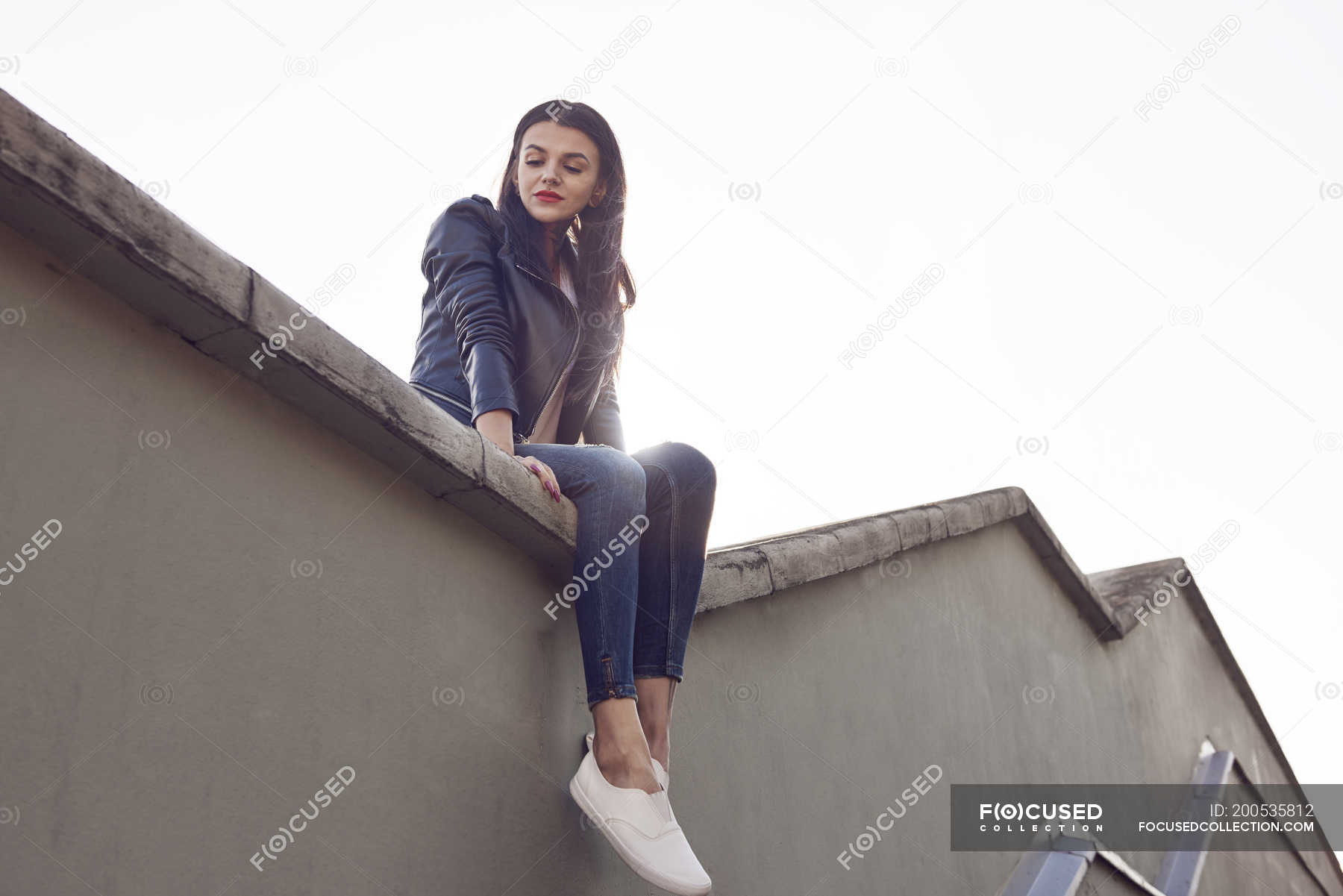 Young woman sitting on roof, low angle view — 25 to 29 years, lifestyle