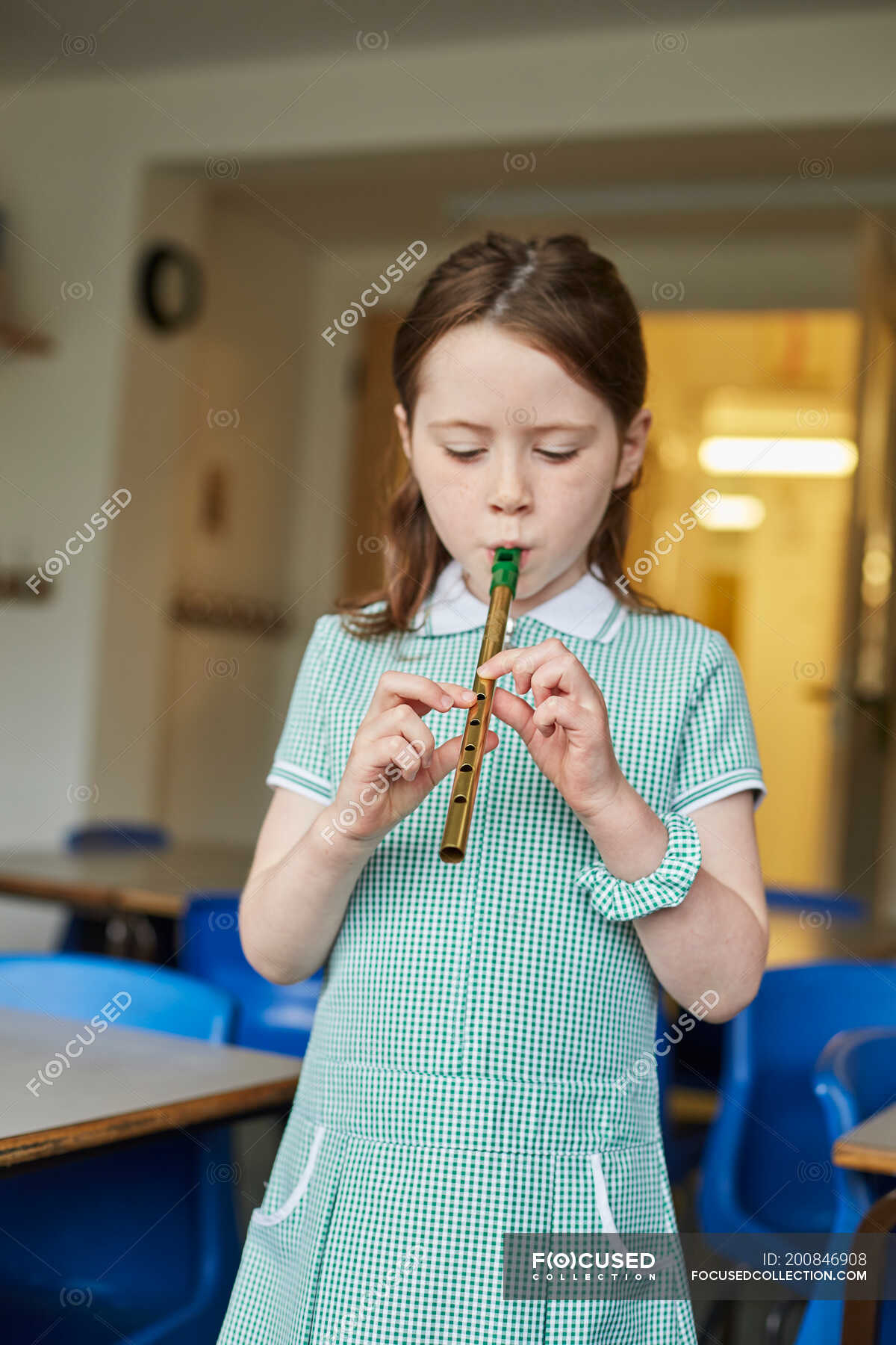 Schoolgirl playing recorder in classroom at primary school — elementary