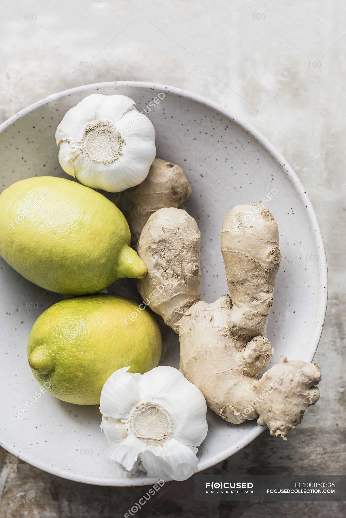 Ginger roots with lemons and garlic in a ceramic bowl, closeup top