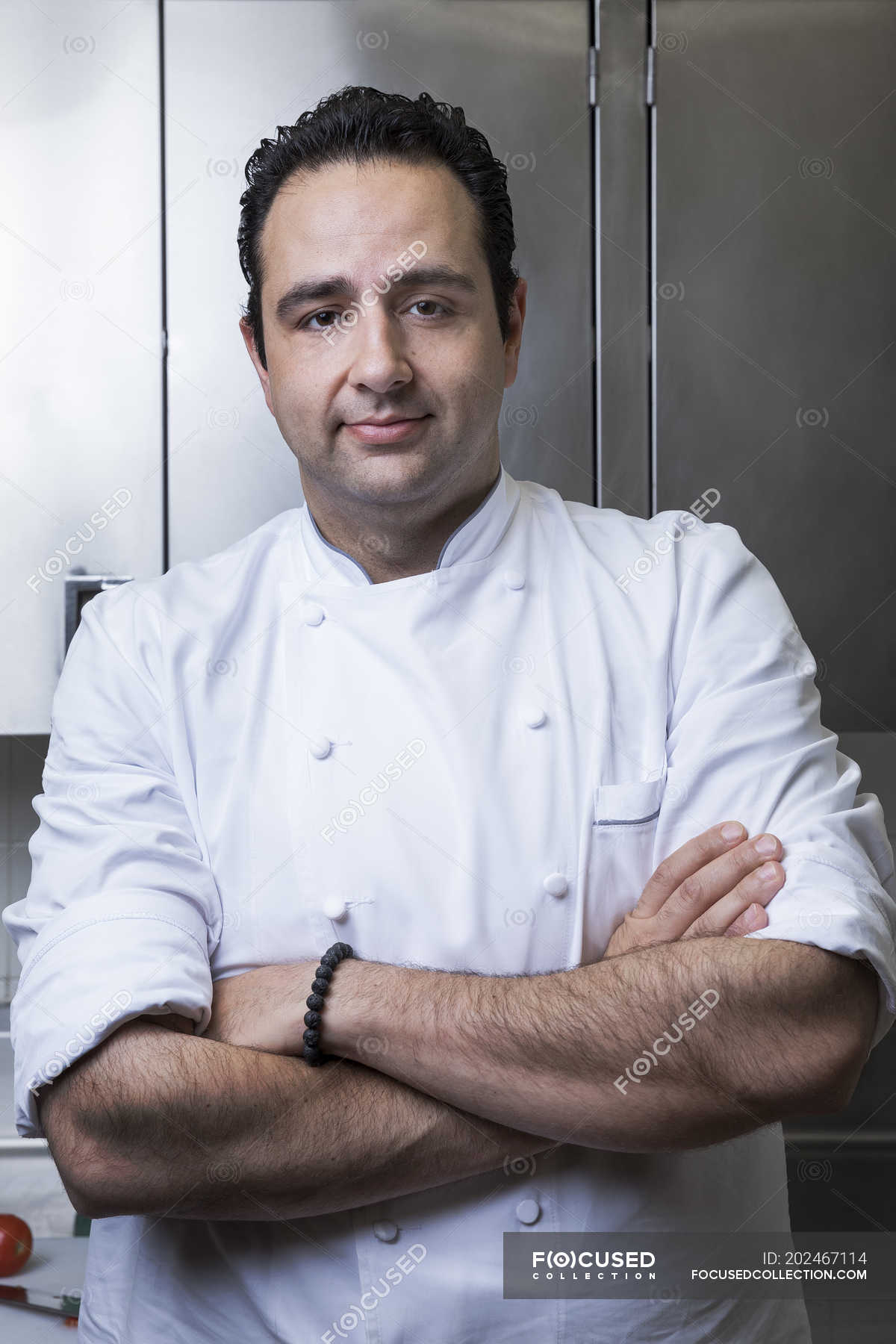 Portrait of chef in commercial kitchen, arms crossed, looking at camera