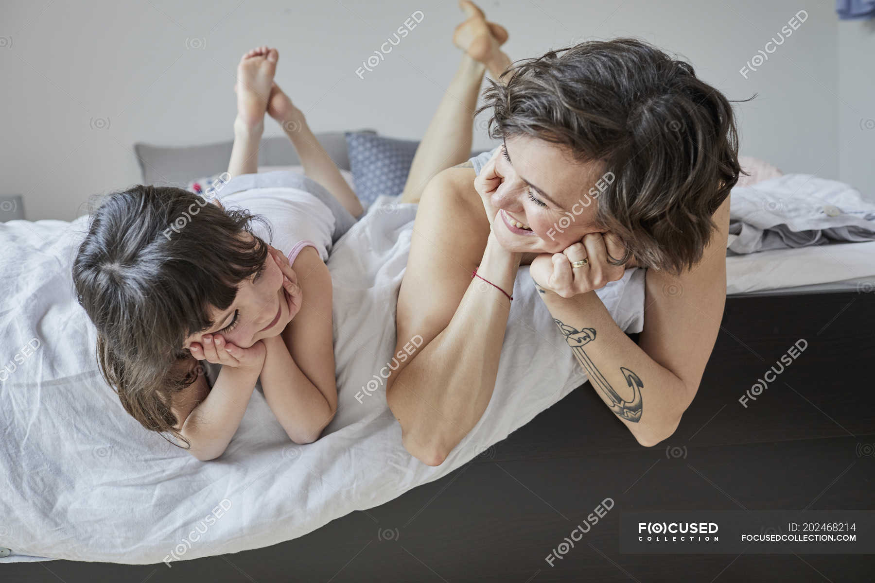Мамаши лежа. Мама с дочкой на кровати. Дочка лежит на маме. Мама и дочь лежат на кровати. Мама лежит на кровати.