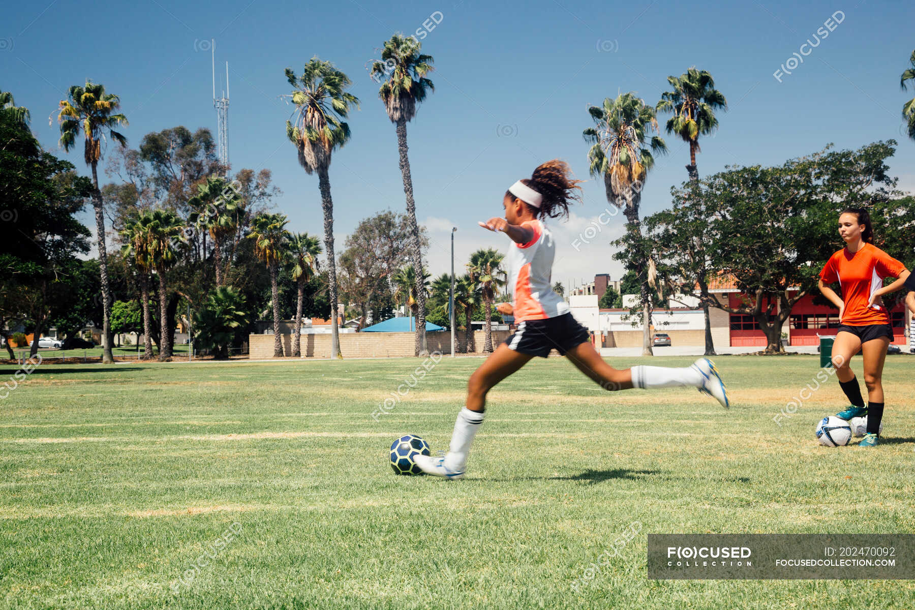 Teenage schoolgirl kicking soccer ball on school sports field ??? 13 to