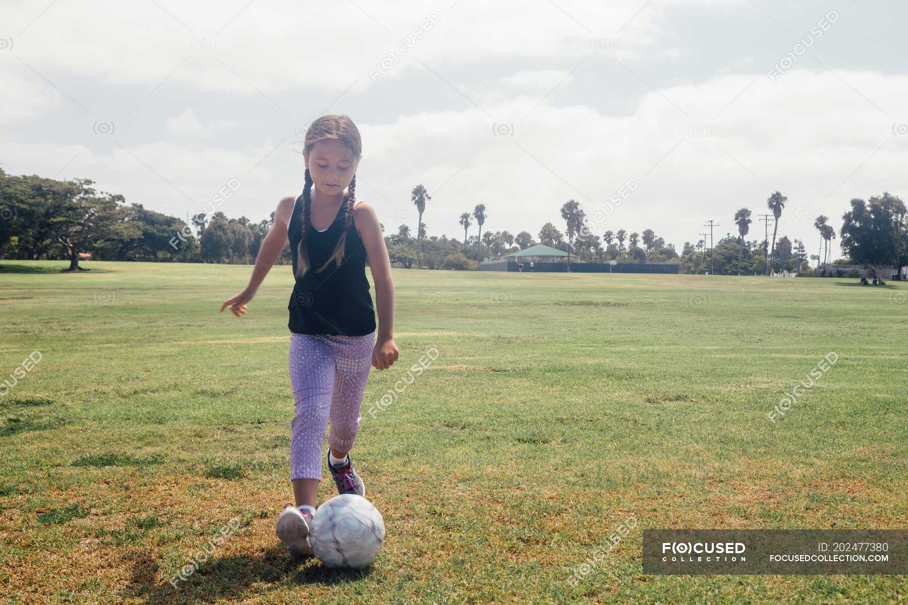Schoolgirl kicking soccer ball on school sports field ??? child