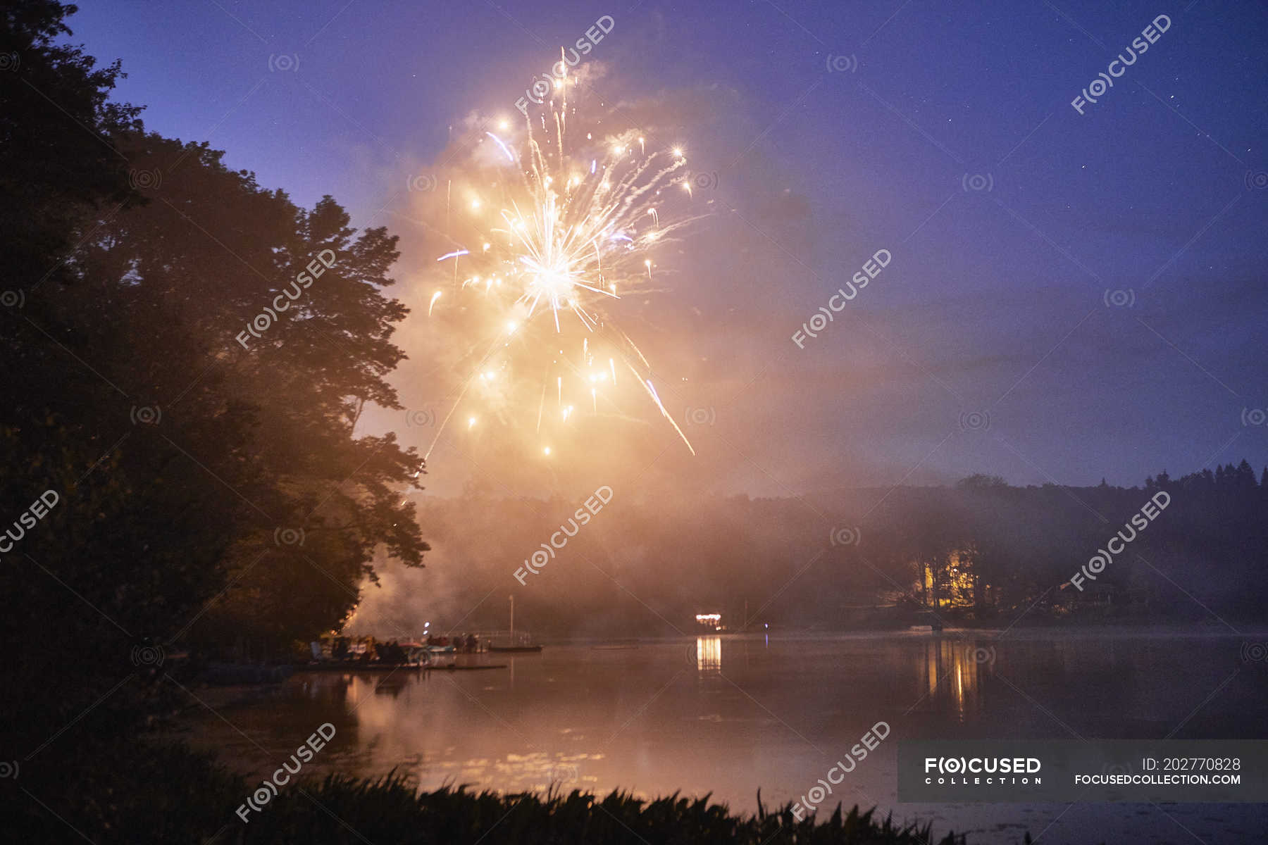 Fireworks exploding over lake at dusk — United States of America