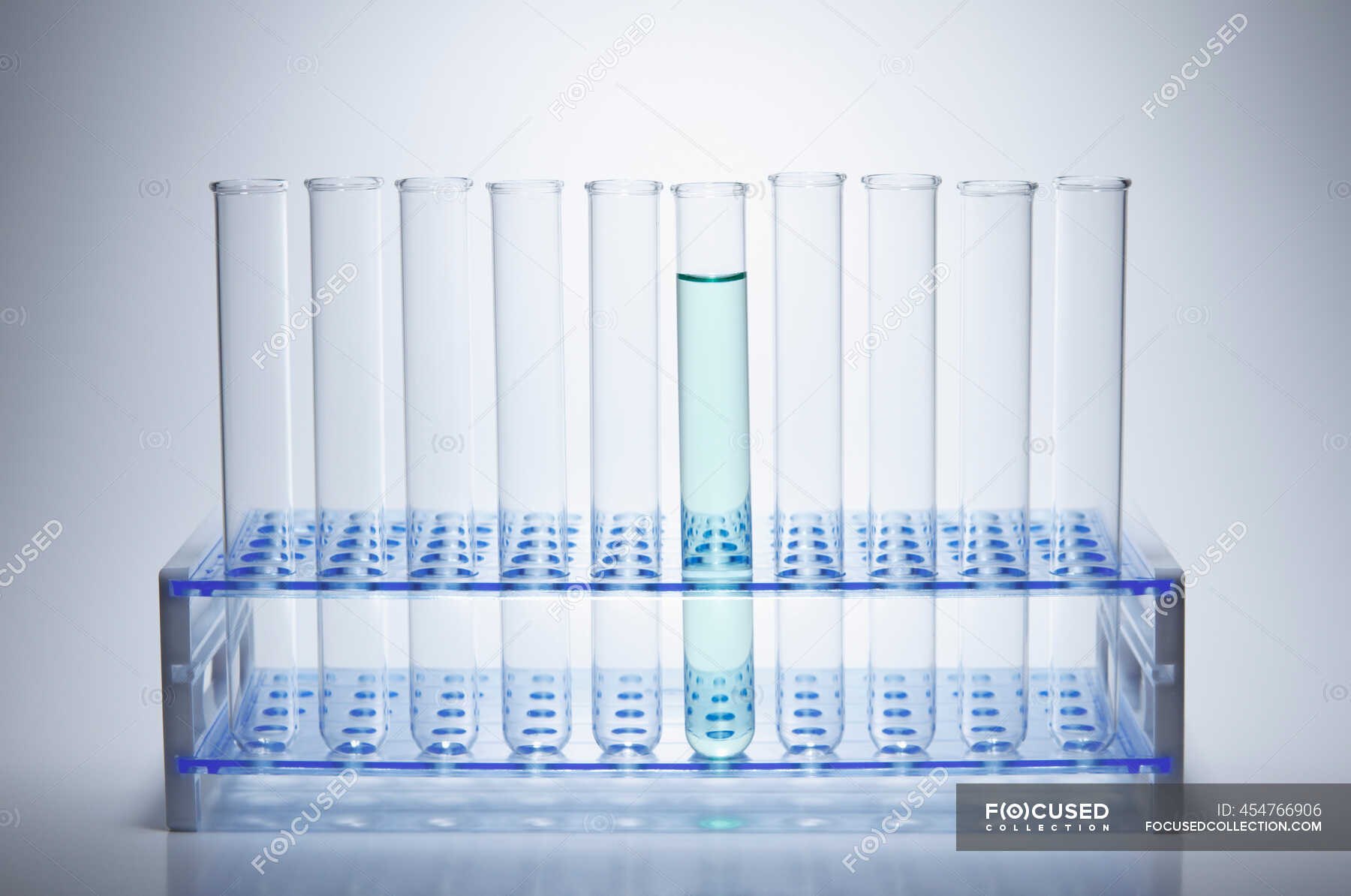 Test tubes in a rack, with one test tube containing green liquid — blue