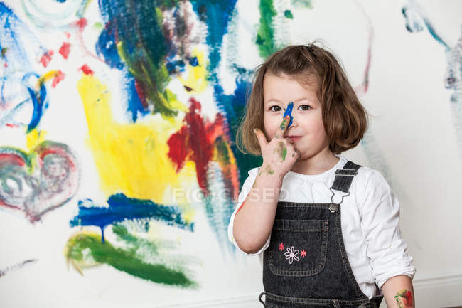 Girl standing in front of painted wall — Stock Photo