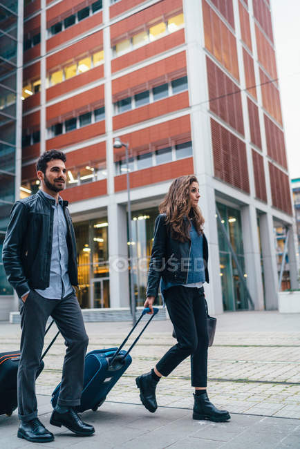 Couple walking with luggage on street — Stock Photo