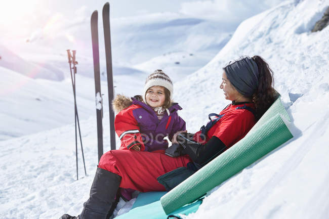 Madre e hija sentadas en la nieve - foto de stock