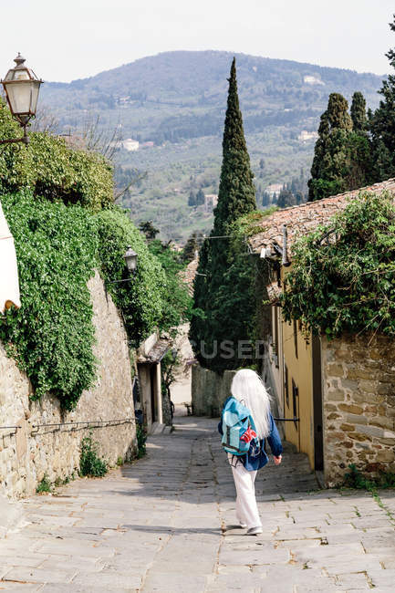 Woman with long grey hair on cobbled street — Stock Photo