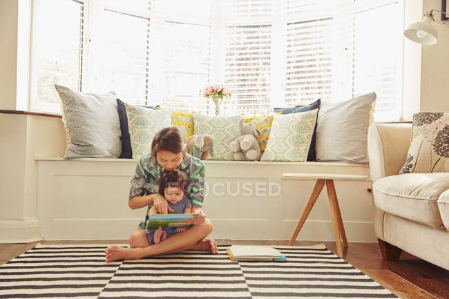 Bébé fille assis sur les mères genoux — Photo de stock