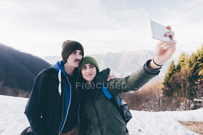 Caminhadas casal tomando selfie em montanhas nevadas — Fotografia de Stock