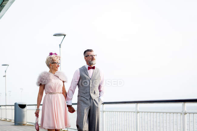 Couple strolling hand in hand on pier — Stock Photo