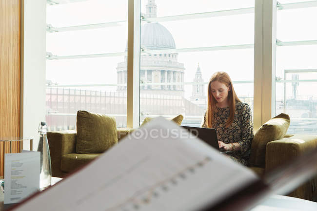 Femme d'affaires utilisant un ordinateur portable sur le canapé de bureau — Photo de stock