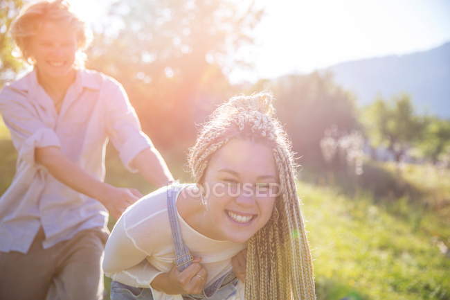 Casal brincando no campo rural iluminado pelo sol — Fotografia de Stock