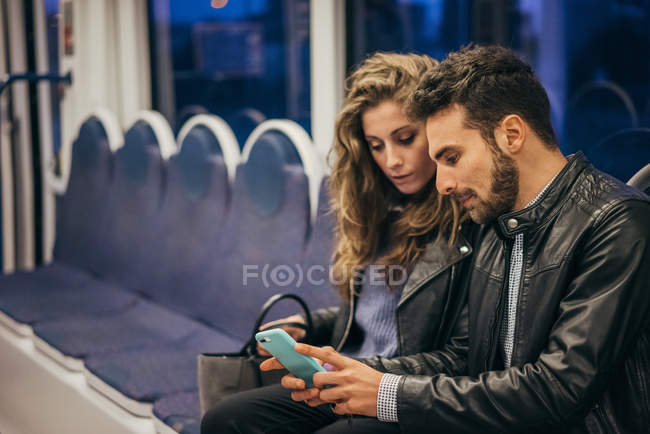 Couple using mobile phone in train — Stock Photo