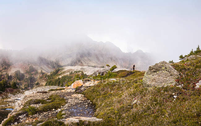 Hiker looking at clouds on mountain peaks — Stock Photo