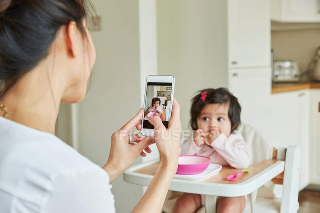 Mujer fotografiando bebé hija - foto de stock