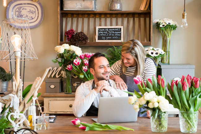 Man using laptop in flower shop — Stock Photo