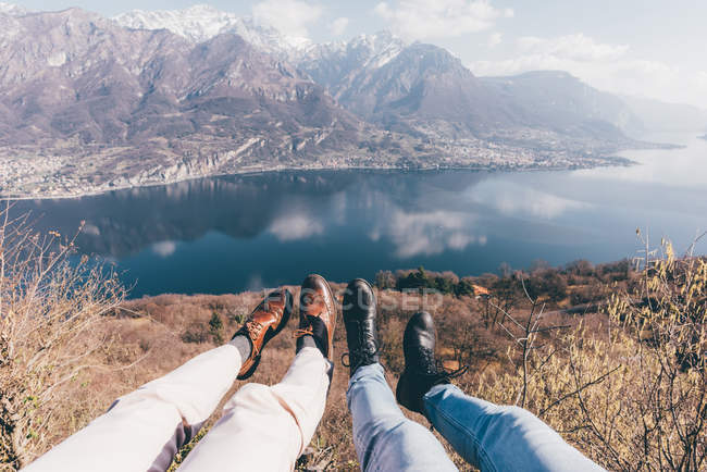 Pernas de casal sobre montanha à beira do lago — Fotografia de Stock